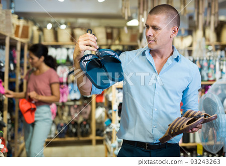 Male shopper chooses beach flip flops at hardware store Male shopper chooses beach flip flops at hardware store 93243263