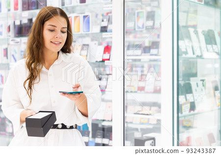 Young woman choosing phone in consumer electronics store Young woman choosing phone in consumer electronics store 93243387