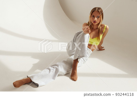 Beautiful Woman Model In Fashionable Outfit Sitting On White Background 93244118