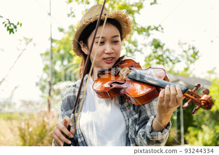 Close-up portrait of Young Asia woman music violinist play violin, relax in the garden with peace of mind Close-up portrait of Young Asia woman music violinist play violin, relax in the garden with peace of mind 93244334