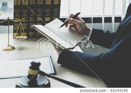 Lawyer hand holding pen and providing legal consult business dispute service at the office with justice scale and gavel hammer 93244336