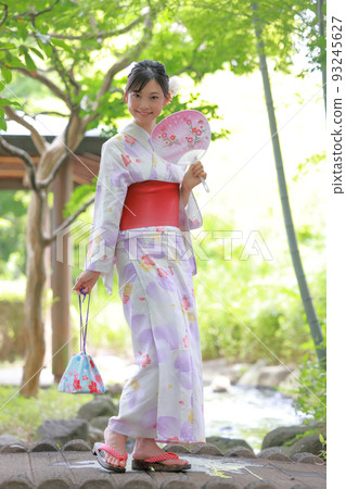 一個穿著浴衣的女人在橋上拿著錢包和扇子微笑 1 93245627