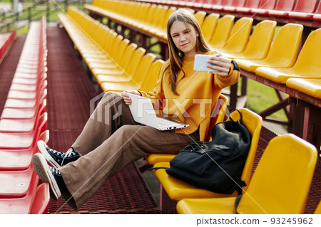 A girl on the seats in the school stands takes a selfie and prepares for classes A girl on the seats in the school stands takes a selfie and prepares for classes 93245962