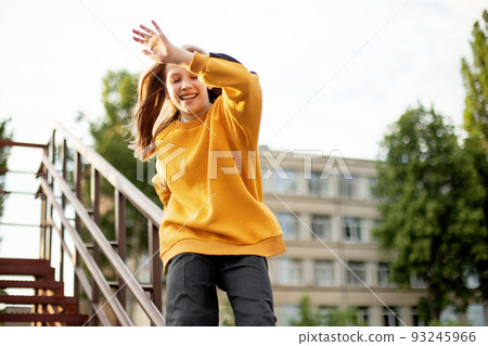 A teenage girl has fun and slides down the railing at the stadium 93245966