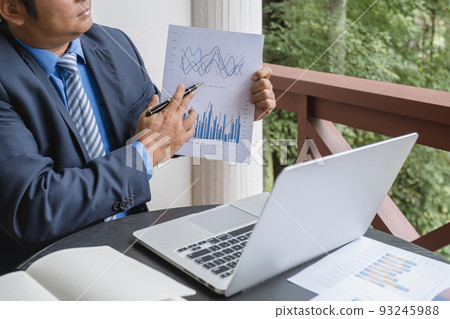 Businessman hand holding pen, analysis the graph with laptop at the home office for setting challenging business goals And planning to achieve the new target 93245988