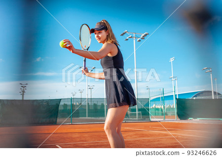 A beautiful young woman plays tennis on the court. Sporting black dress suit. The girl smiles, happy. The athlete delivers the ball. Team play, training, active outdoor lifestyle. grid A beautiful young woman plays tennis on the court. Sporting black dress suit. The girl smiles, happy. The athlete delivers the ball. Team play, training, active outdoor lifestyle. grid 93246626