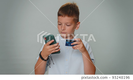 Teen boy using credit bank card and smartphone while transferring money, purchases online shopping Teen boy using credit bank card and smartphone while transferring money, purchases online shopping 93248196