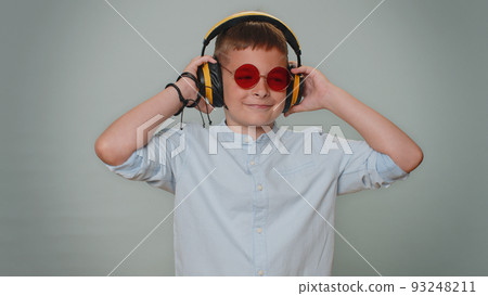 Cheerful toddler boy listening music via headphones and dancing disco fooling around having fun 93248211