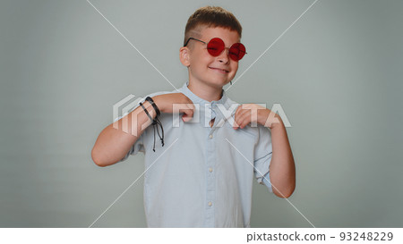 Seductive cheerful toddler stylish boy child in shirt wearing sunglasses charming smile on blue wall 93248229