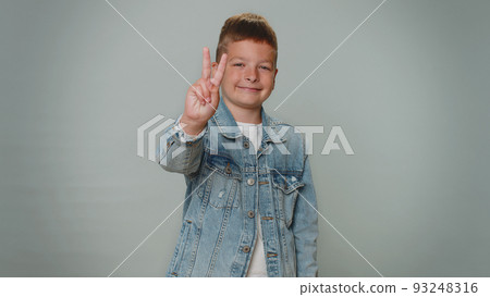 Toddler lovely boy showing victory sign, hoping for success and win, doing peace gesture, smiling Toddler lovely boy showing victory sign, hoping for success and win, doing peace gesture, smiling 93248316