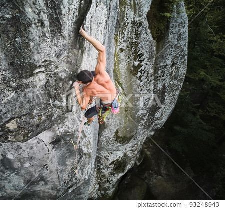 Young man climber climbing difficult route on high boulder with rope. Fearless rock climber training rock climbing on summer day. Concept of extreme sport, adventures and active lifestyle. Aerial view Young man climber climbing difficult route on high boulder with rope. Fearless rock climber training rock climbing on summer day. Concept of extreme sport, adventures and active lifestyle. Aerial view 93248943