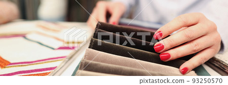 Woman chooses fabric in furniture store closeup Woman chooses fabric in furniture store closeup 93250570