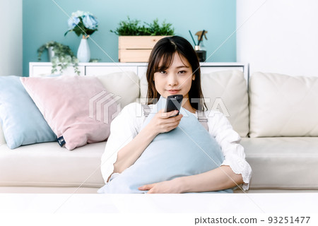 一個微笑著看電視的女人看著相機 一個微笑著看電視的女人看著相機 93251477