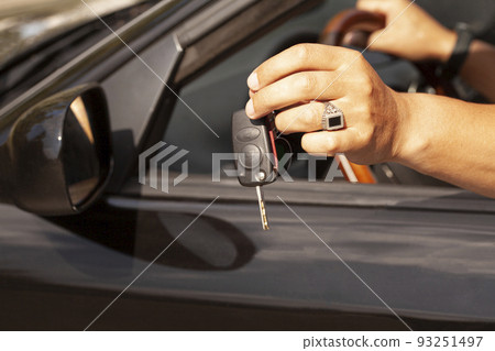 Car key in a man's hand with car. 93251497