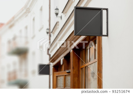 Blank signboard mock up, on the facade. Copy space for your store sign or logo. Modern empty outdoor signage, mockup to add company logo. Black square store signboard on white wall. 93251674