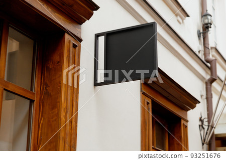 Blank signboard mock up, on the facade. Copy space for your store sign or logo. Modern empty outdoor signage, mockup to add company logo. Black square store signboard on white wall. 93251676