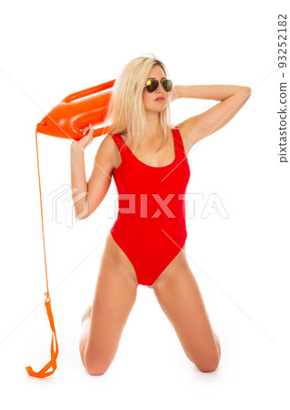 Pretty young blonde lifeguard in red sexy swimsuit with lifeguard rescue can floating buoy tube on the white background. Concept Woman in Swimsuite. Pretty young blonde lifeguard in red sexy swimsuit with lifeguard rescue can floating buoy tube on the white background. Concept Woman in Swimsuite. 93252182