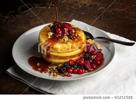 Close up of Pancakes with forest fruits berries on wooden table.Blueberries, raspberries on pancakes with maple syrup. Concept morning protein breakfast. Close up of Pancakes with forest fruits berries on wooden table.Blueberries, raspberries on pancakes with maple syrup. Concept morning protein breakfast. 93252588