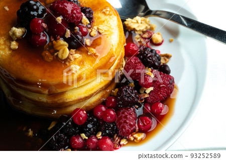 Close up of Pancakes with forest fruits berries on wooden table.Blueberries, raspberries on pancakes with maple syrup. Concept morning protein breakfast. Close up of Pancakes with forest fruits berries on wooden table.Blueberries, raspberries on pancakes with maple syrup. Concept morning protein breakfast. 93252589