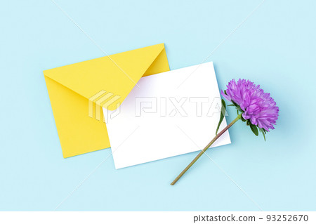 White blank card, yellow envelope and purple flower on blue background. Minimal style. Top view Flat lay Mockup 93252670
