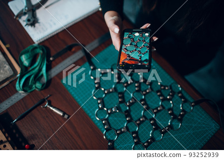 Tanner woman making leather harness take photo mobile cell phone on workshop. Working process of leather craftsman. 93252939