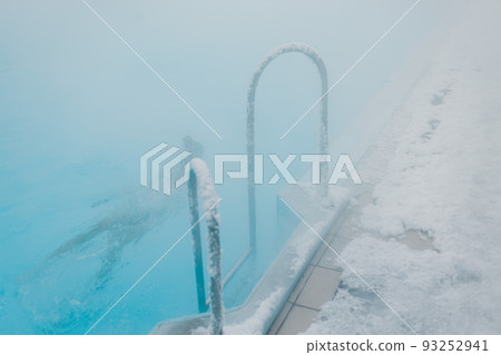 Fit swimmer male training swim in open winter swimming pool with fog. Geothermal outdoor spa health concept. 93252941