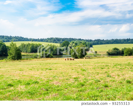 mowed meadow next to small river and green hills 93255313