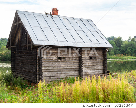old log cabin on riverbank on summer day old log cabin on riverbank on summer day 93255347