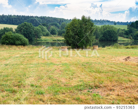 hay bales on mowed meadow near river in summer 93255363