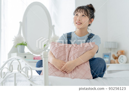 Portrait of a high school girl cross-legged on the bed and smiling 93256123