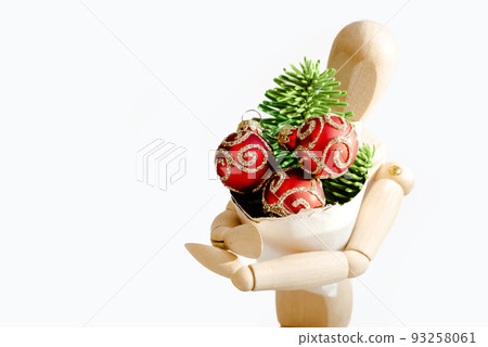 Wooden dummy holds cone with fresh fir twig and three shiny red balls, christmas gift, holiday shopping, new year celebration Wooden dummy holds cone with fresh fir twig and three shiny red balls, christmas gift, holiday shopping, new year celebration 93258061