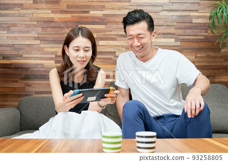 Men and women playing with portable game machines Men and women playing with portable game machines 93258805