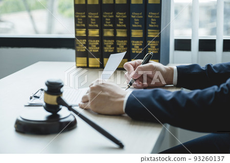 Lawyer hand holding pen and providing legal consult business dispute service at the office with justice scale and gavel hammer Lawyer hand holding pen and providing legal consult business dispute service at the office with justice scale and gavel hammer 93260137
