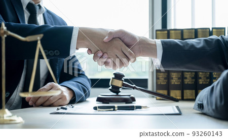 Handshake after Lawyer  providing legal consult business dispute service to the man at the office with justice scale and gavel hammer 93260143