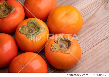 A photo of a persimmon on a wooden board 93260587