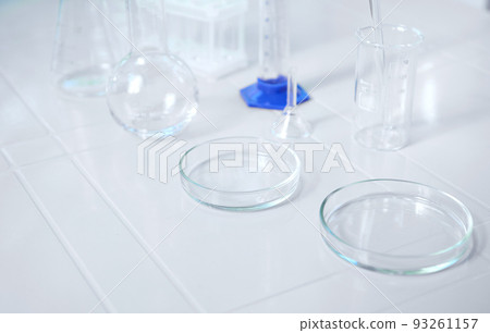 Glass lab dishes on white table on the background of labware such as beaker, flask, graduated cylinders, test tubes. Science chemistry. Scientific biological and chemical laboratory with copy ad space Glass lab dishes on white table on the background of labware such as beaker, flask, graduated cylinders, test tubes. Science chemistry. Scientific biological and chemical laboratory with copy ad space 93261157