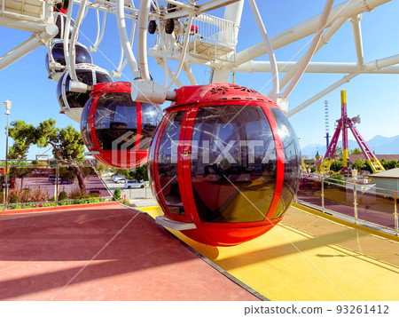 on the Ferris wheel there are large cabins for skiing tourists of red color with black, tinted windows to protect from the sun's rays. boarding tourists 93261412