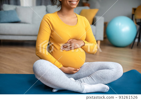 Body care and workout. Smiling young pregnant black lady touch big belly, feels movement of baby 93261526