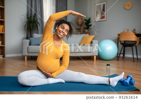 Motherhood and workout. Glad pretty millennial pregnant african american lady practicing yoga Motherhood and workout. Glad pretty millennial pregnant african american lady practicing yoga 93261614