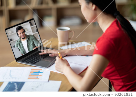 Busy adolescent asian lady study at table with laptop with arabic teacher in room interior. Education and online lecture 93261831