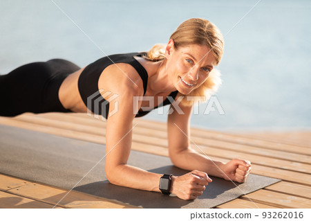 Beautiful Middle Aged Woman Training On Pier Outdoors, Standing In Plank Position Beautiful Middle Aged Woman Training On Pier Outdoors, Standing In Plank Position 93262016