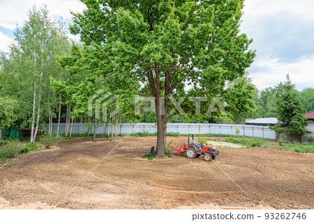 Minitractor on a cultivated plot of land next to a tree Minitractor on a cultivated plot of land next to a tree 93262746