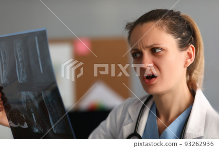 Female doctor looks in amazement and shock at x-ray of spine Female doctor looks in amazement and shock at x-ray of spine 93262936