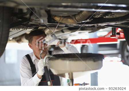 Auto mechanic checks running gear of car and oil leak at service station Auto mechanic checks running gear of car and oil leak at service station 93263024