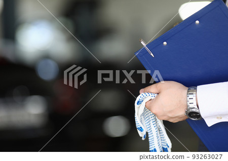 Car mechanic priemchik holds gloves and clipboard in car service Car mechanic priemchik holds gloves and clipboard in car service 93263027