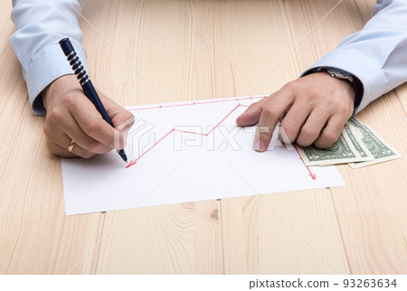 The hands of a man dressed on blue office t-shirt with classic wrist watch and golden ring on his hands draws using red pencil a chart of rising stock prices. Close-up of the hands of a man . The hands of a man dressed on blue office t-shirt with classic wrist watch and golden ring on his hands draws using red pencil a chart of rising stock prices. Close-up of the hands of a man . 93263634