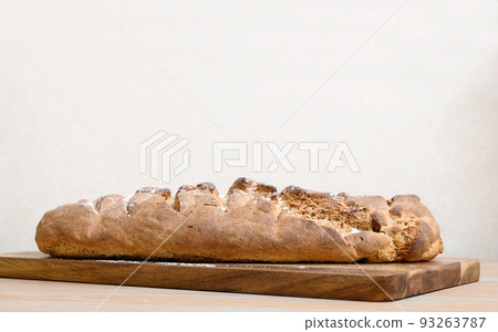 Close-up of freshly cooked delicious hot fresh handmade bread which lies on a wooden board in a home kitchen. Close-up of freshly cooked delicious hot fresh handmade bread which lies on a wooden board in a home kitchen. 93263787
