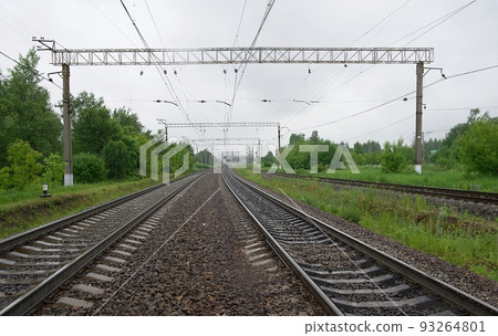 Wet railroad rails and sleepers in rainy weather on a summer day and gray low clouds in the sky. 93264801