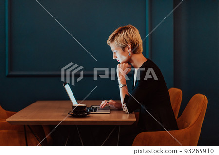 Businesswoman sitting in a cafe while focused on working on a laptop and participating in an online meetings. Selective focus. High quality photo Businesswoman sitting in a cafe while focused on working on a laptop and participating in an online meetings. Selective focus. High quality photo 93265910
