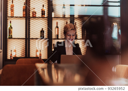 Businesswoman sitting in a cafe while focused on working on a laptop and participating in an online meetings. Selective focus. High quality photo 93265952
